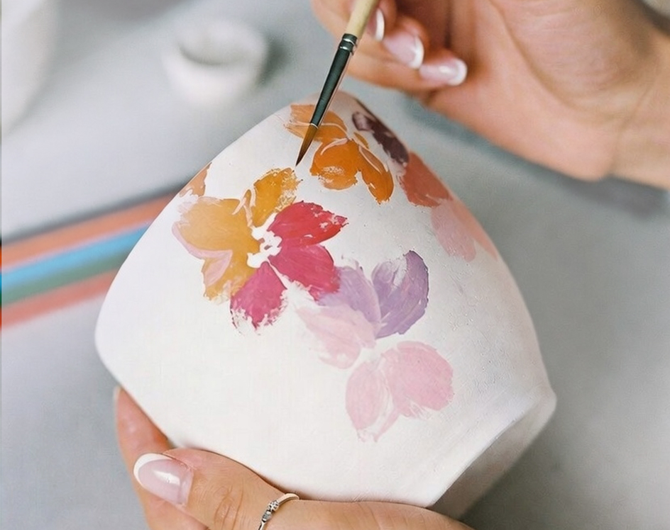 iemand beschilderd gekleurde bloemetjes op een keramieken mok