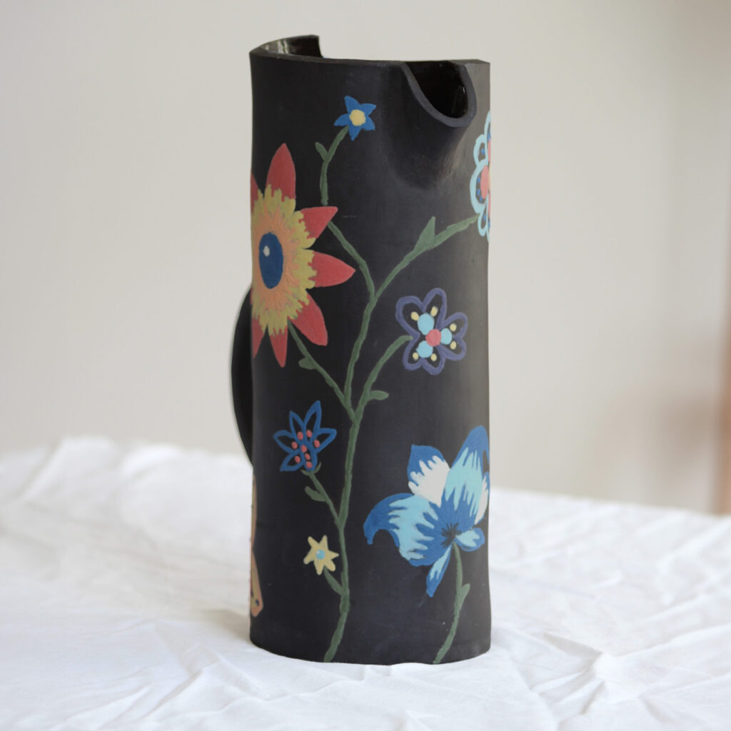 water kan met gekleurde bloemen erop geschilderd