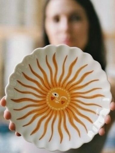 Een vrouw houdt een beschilderd keramiek bordje vast.